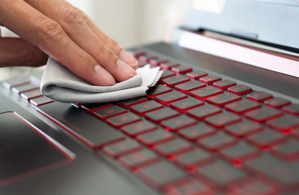 Imagem mostra mão passando pano para limpar notebook