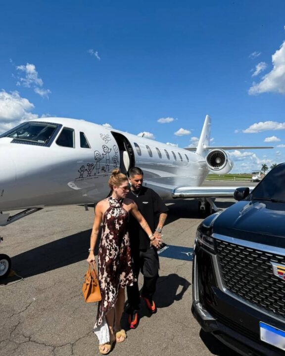 Zé Felipe e Virginia pousando para foto ao lado do avião e carro deles 
