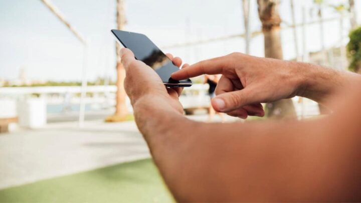 Imagem de das mãos de alguém que segura e mexe na tela do celular