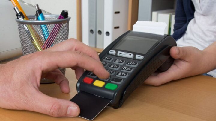 Pessoa inserindo cartão de crédito na maquininha de pagamento