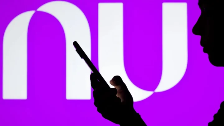 Pessoa usando celular em frente logomarca do Nubank