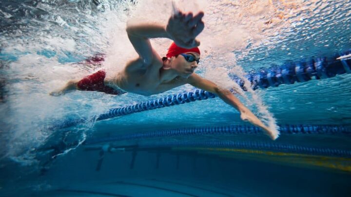Bolhas de água demonstrando velocidade. Jovem, atleta de natação em movimento durante o treinamento na piscina, preparando-se para a competição. Conceito de esporte profissional, saúde, resistência, força, estilo de vida ativo.