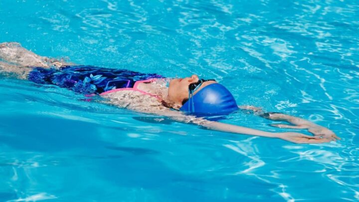 Mulher esportiva em óculos nadando de volta na piscina