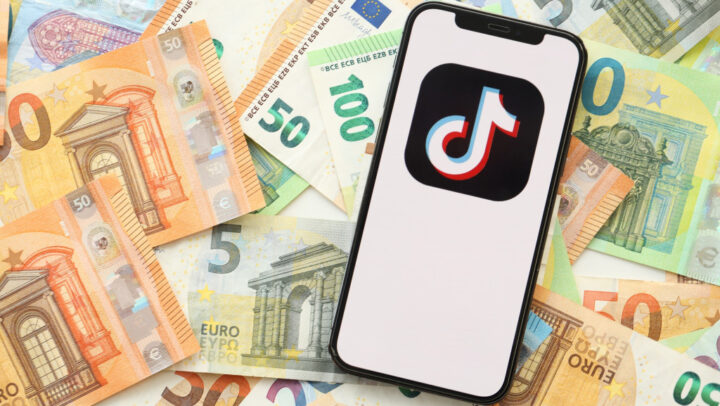 Smartphone com o logo do TikTok exibido na tela e em cima de notas de dinheiro