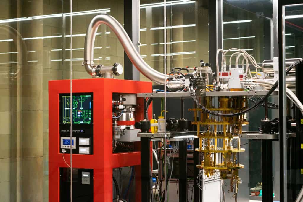 Computador quântico instalado em laboratório, com estrutura metálica, cabos e sistema de refrigeração.